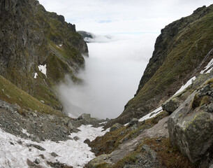 Clouds over the valley, a journey along a trail in the high mountains.
