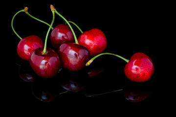 Fresh cherries on a black background with reflection. 