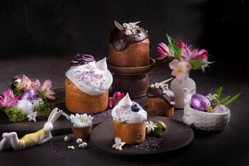 Easter cakes with icing on a dark background among flowers
