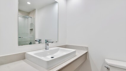 Clean, modern bathroom showcasing a white sink, large mirror, and bright, minimalist design style.