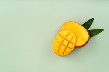 Fresh ripe mango with cubes on green table background.