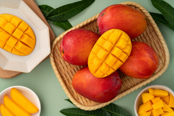 Fresh ripe mango with cubes on green table background.
