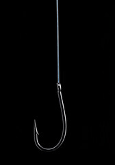 Close-up of a shiny fishing hook hanging from a fishing line.