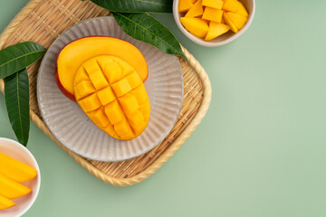 Fresh ripe mango with cubes on green table background.