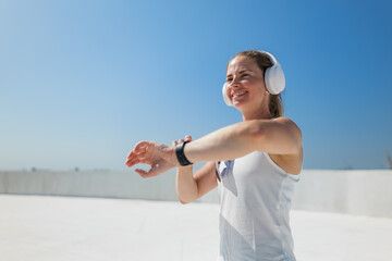 Joyful woman enjoys morning workout on rooftop under clear blue sky