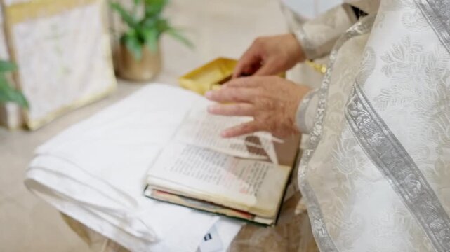A priest, dressed in sacred garments, conducts a solemn baptism ceremony using a water basin and candles