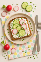 Whole grain toast with cottage cheese, cucumber, radish, and chives on a pastel polka dot napkin