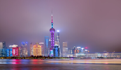 Obraz premium Shanghai colorful skyline with motion speed light of passing ferry in the foreground at night - Shanghai, China