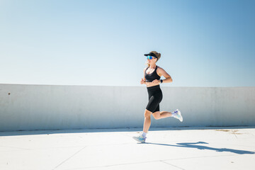 Energetic woman runs along a bright rooftop under a clear blue sky