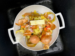 A kitchen sink with vegetable scraps, peelings, the food waste ready for disposal