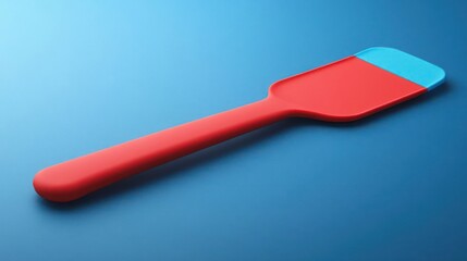 Elevated view of a vibrant red and blue silicone spatula against a sleek gradient blue surface, perfect for showcasing culinary tools with a modern aesthetic and crisp lines