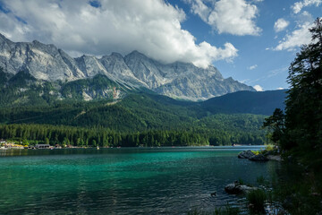 Obraz premium Eibsee lake and Zugspitze in Bavaria under a bright blue sky surrounded by green forest and peaks
