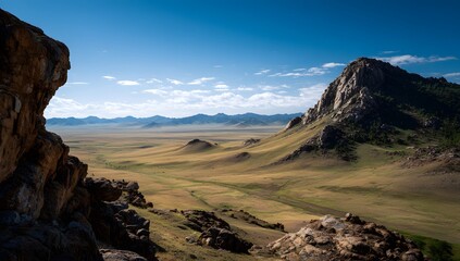 Wide open steppe landscape with rocky mountains under clear blue sky