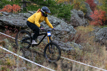 Fototapeta premium woman mountain biker riding downhill on rocky trail during race competition