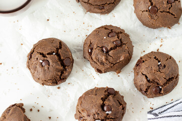 Homemade chocolate chip cookies on white parchment paper background. Top view.
