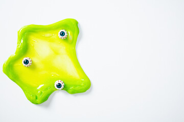 Bright green slime with scary eyeballs on white background. Happy Halloween minimal concept.
