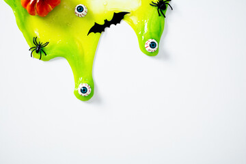 Dripping green slime with scary eyeballs, spiders, bat cutout, and pumpkin on white background....