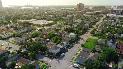 Elevated view Galveston residential grid, hospital buildings, port infrastructure with cranes....
