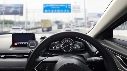 Interior dashboard view from a car driving on a busy highway, showing traffic, speedometer, and...