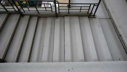 Obraz premium Building Urban stairwell structure with repeating concrete steps and metal guardrails viewed from top down angle