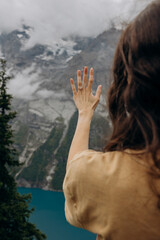 Woman Admiring Engagement Ring with Scenic Lake and Snow-Capped Mountains, Symbolizing Romantic Marriage Proposal
