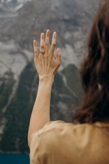 Woman Admiring Engagement Ring with Scenic Lake and Snow-Capped Mountains, Symbolizing Romantic Marriage Proposal