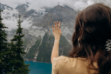 Woman Admiring Engagement Ring with Scenic Lake and Snow-Capped Mountains, Symbolizing Romantic Marriage Proposal
