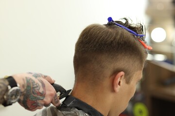 Professional barber making stylish haircut in barbershop, closeup
