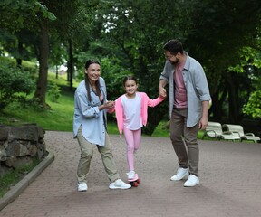 Obraz premium Happy family having fun with penny board in park