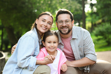 Family portrait of smiling parents and daughter outdoors