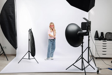 Little girl on white background in photo studio with professional equipment