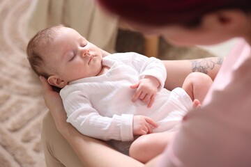 Mom holding her sleeping newborn baby at home, above view
