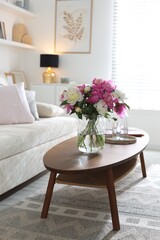 Bouquet of beautiful peonies and water on coffee table indoors. Interior design