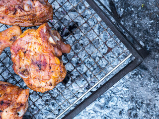 Chicken legs grilling on barbecue grill over hot coals