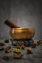 Tibetan singing bowl on a blue cushion with dried flowers and a wooden mallet, creating a serene atmosphere for meditation and relaxation