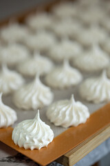 Hand-piped meringues aligned on silicone baking sheet