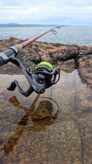 Spinning Fishing Rod and reel on Coastal Rocks with Ocean in Background  Outdoor Angling Scene, Coastal Fishing Adventure