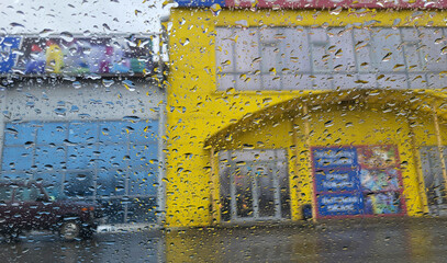 Transparent raindrops on the window. View through a rain-soaked window at a blurred background with...