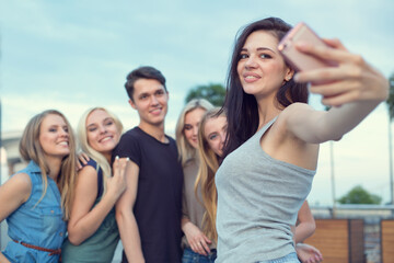 Fototapeta premium Best friends taking selfie portrait outdoors. Happy friendship concept with young people having fun together. Group of friends make selfie photo with smart phone camera while traveling on vacation.