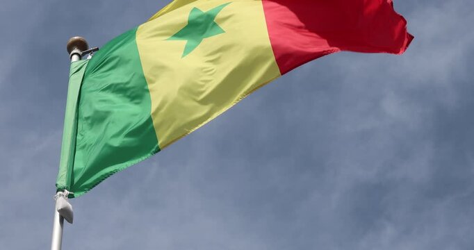 The Senegalese flag is captured in close-up. The flag of Senegal, flying against the blue sky, is the national symbol of Senegal. Great for news. The video is presented in 4K format.