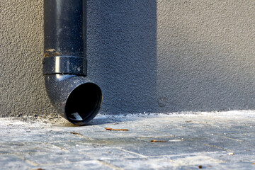 Plastic drain pipe on a gray plastered wall.Rain runoff.