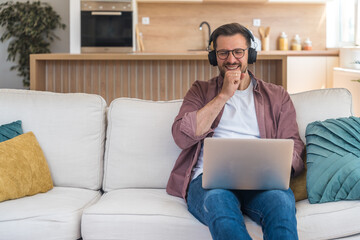 Winner business mindset. Young freelance businessman sitting at home on sofa, working on laptop...