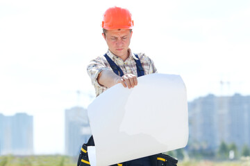 Male builder. Man builder in hardhats with clipboard and blueprint on outdoors. Concept....