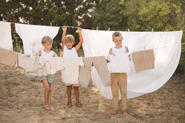 Village boys hanging laundry on clotheslines with wooden clothespins on a sunny summer day. Rural...
