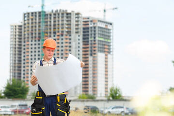 Looking at blueprints in a building site. Man builder in hardhats with clipboard and blueprint on...
