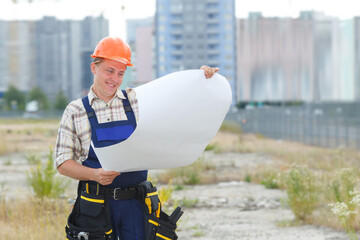 Looking at blueprints in a building site. Man builder in hardhats with clipboard and blueprint on...