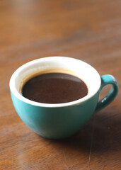 Black coffee in a glass on a wooden table