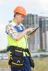 Portrait man construction worker. Male engineer construction. Contractor at a building site. Male construction worker at a building site. Business. Construction foreman working with electronic tablet.