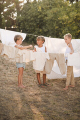 Village boys hanging laundry on clotheslines with wooden clothespins on a sunny summer day. Rural...