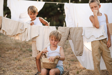 Village boys hanging laundry on clotheslines with wooden clothespins on a sunny summer day. Rural...